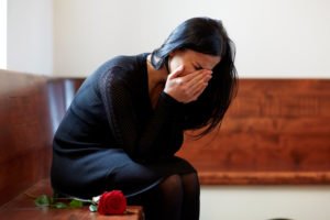a grieving woman cries at a funeral